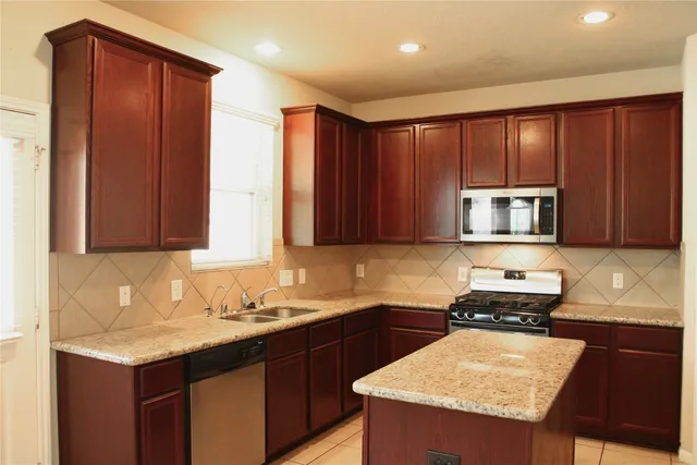 a view of an empty room with chandelier fan and fire place