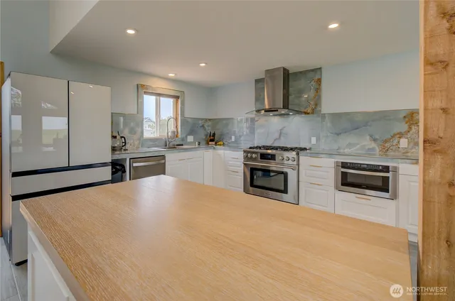 a large kitchen with stainless steel appliances granite countertop a stove a sink and a microwave