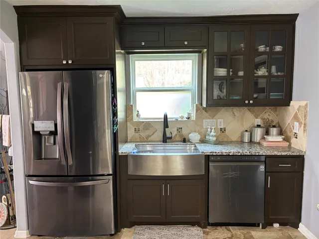 a kitchen with granite countertop stainless steel appliances a refrigerator and a sink