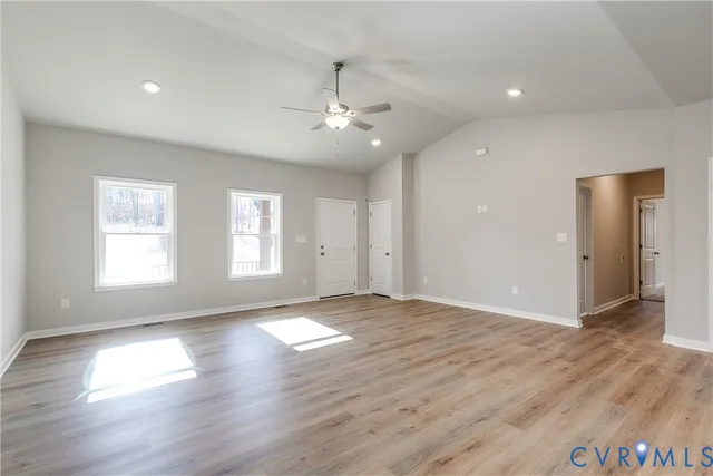 a view of an empty room with window and wooden floor