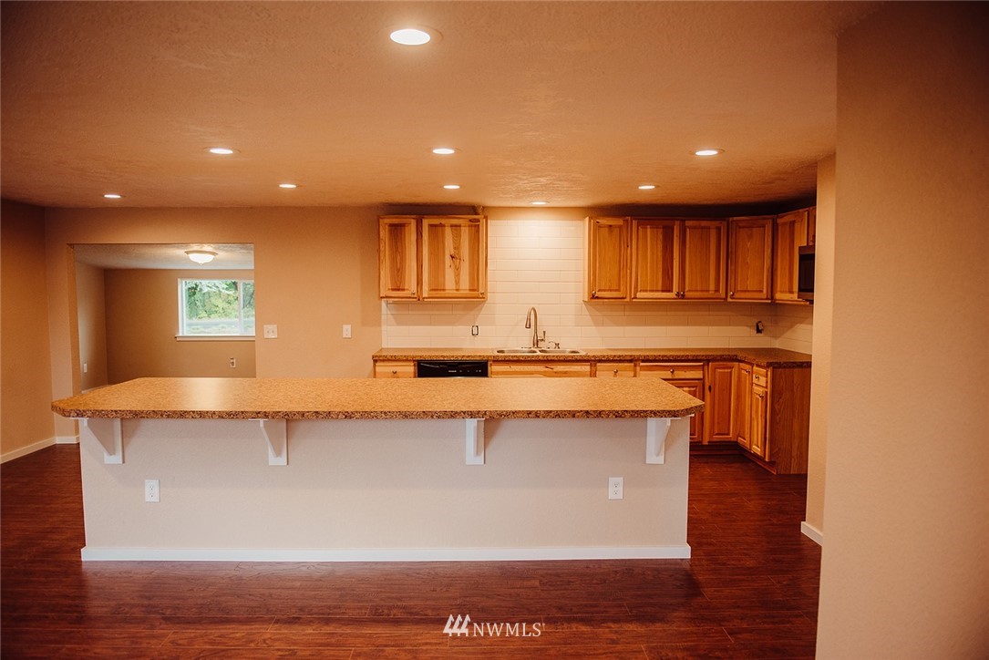 116 Eadon Road Toledo, WA 98591 - Photo 8 of 34 a view of a kitchen with kitchen island a sink wooden floor and a counter top space