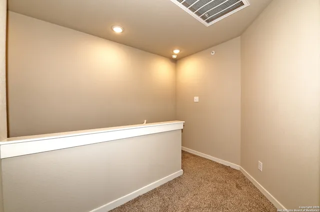 an empty room with a chandelier fan and windows