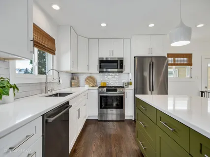 a kitchen with kitchen island granite countertop a sink a counter space stainless steel appliances and cabinets