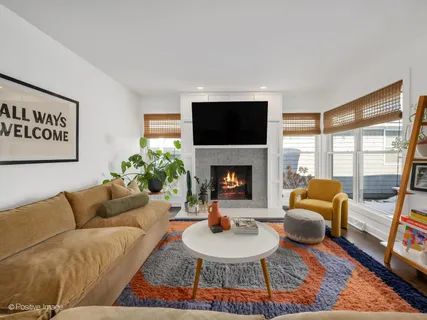 a living room with furniture a rug a fireplace and a large window