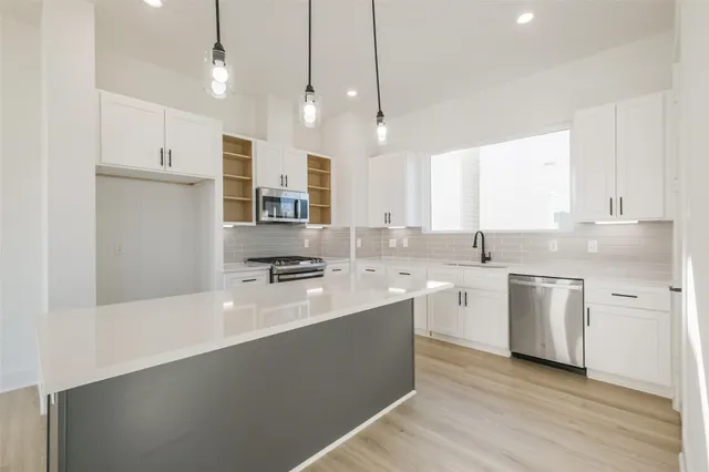 a kitchen with kitchen island a sink stainless steel appliances and white cabinets
