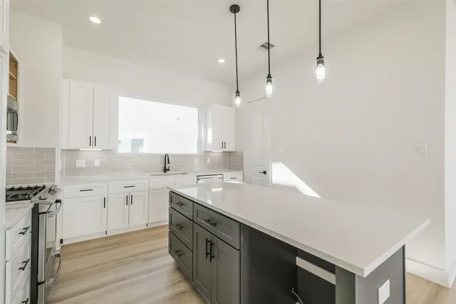a kitchen with a sink dishwasher and white cabinets with wooden floor