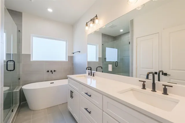a bathroom with a bathtub a double vanity sink and mirror