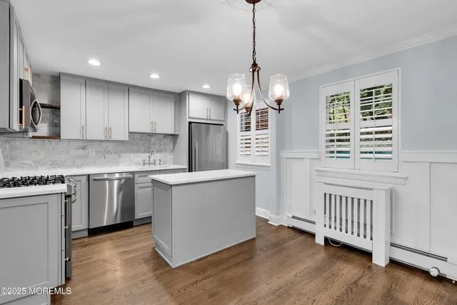 a kitchen with stainless steel appliances granite countertop a stove a sink dishwasher a refrigerator and white cabinets with wooden floor