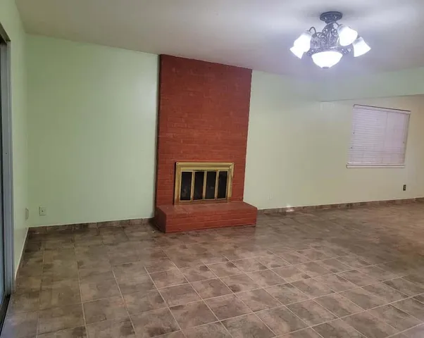 a view of an empty room with a chandelier fan