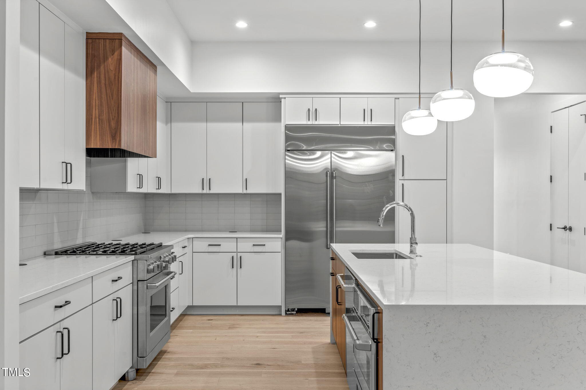 1406 Lyon Street, Unit 102 Raleigh, NC 27608 - Photo 4 of 57 a kitchen with kitchen island granite countertop a sink a stove and cabinets