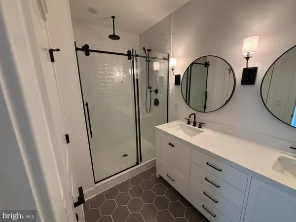 a bathroom with a double vanity sink mirror and shower