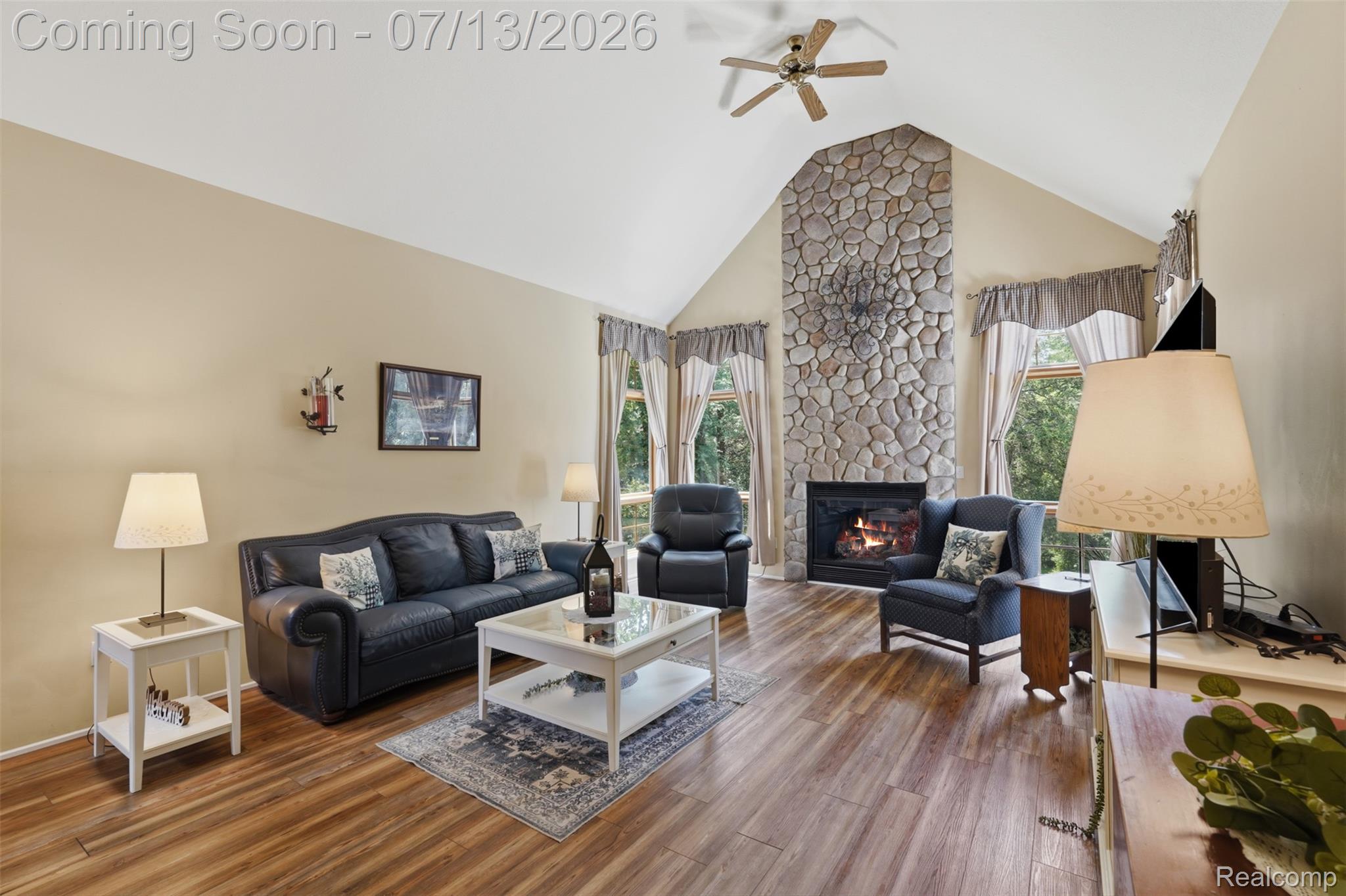 10525 Antcliff Road Brooklyn, MI 49230 - Photo 10 of 80 Spacious living area featuring a stone fireplace, vaulted ceiling, and peaceful views of nature