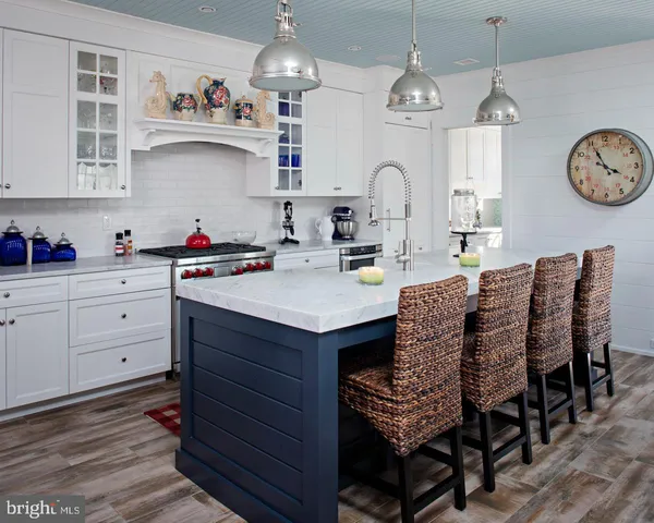 a very nice looking kitchen with granite countertop a stove a oven a sink a dining table and chairs with wooden floor