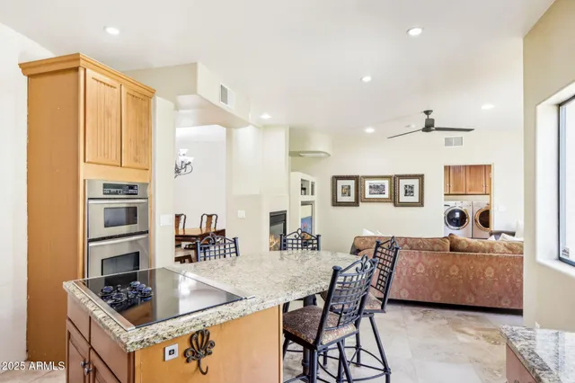 a living room with stainless steel appliances furniture a rug and a kitchen view