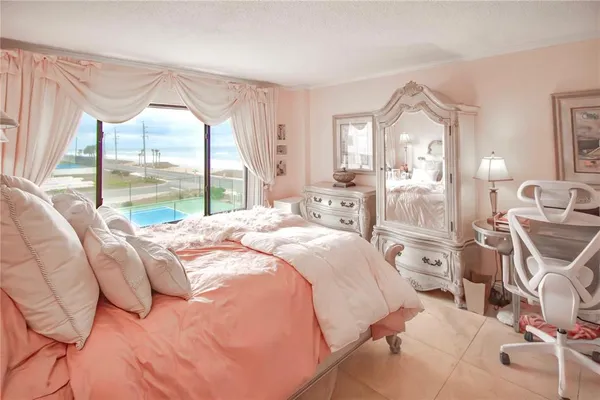 a bedroom with a bed a large window with table and chairs