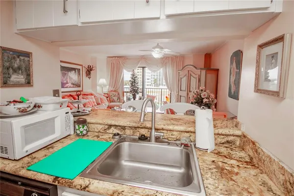 a kitchen with a sink a counter top space and living room view