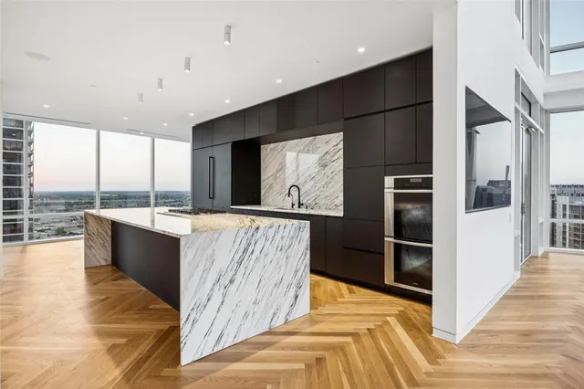 a view of kitchen with kitchen island granite countertop a refrigerator a sink and a stove top oven