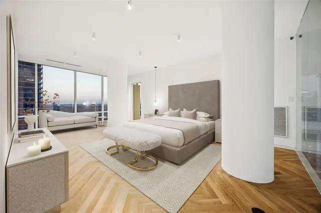 a spacious bedroom with a bed and wooden floor