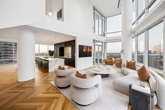 a living room with furniture large windows and kitchen view