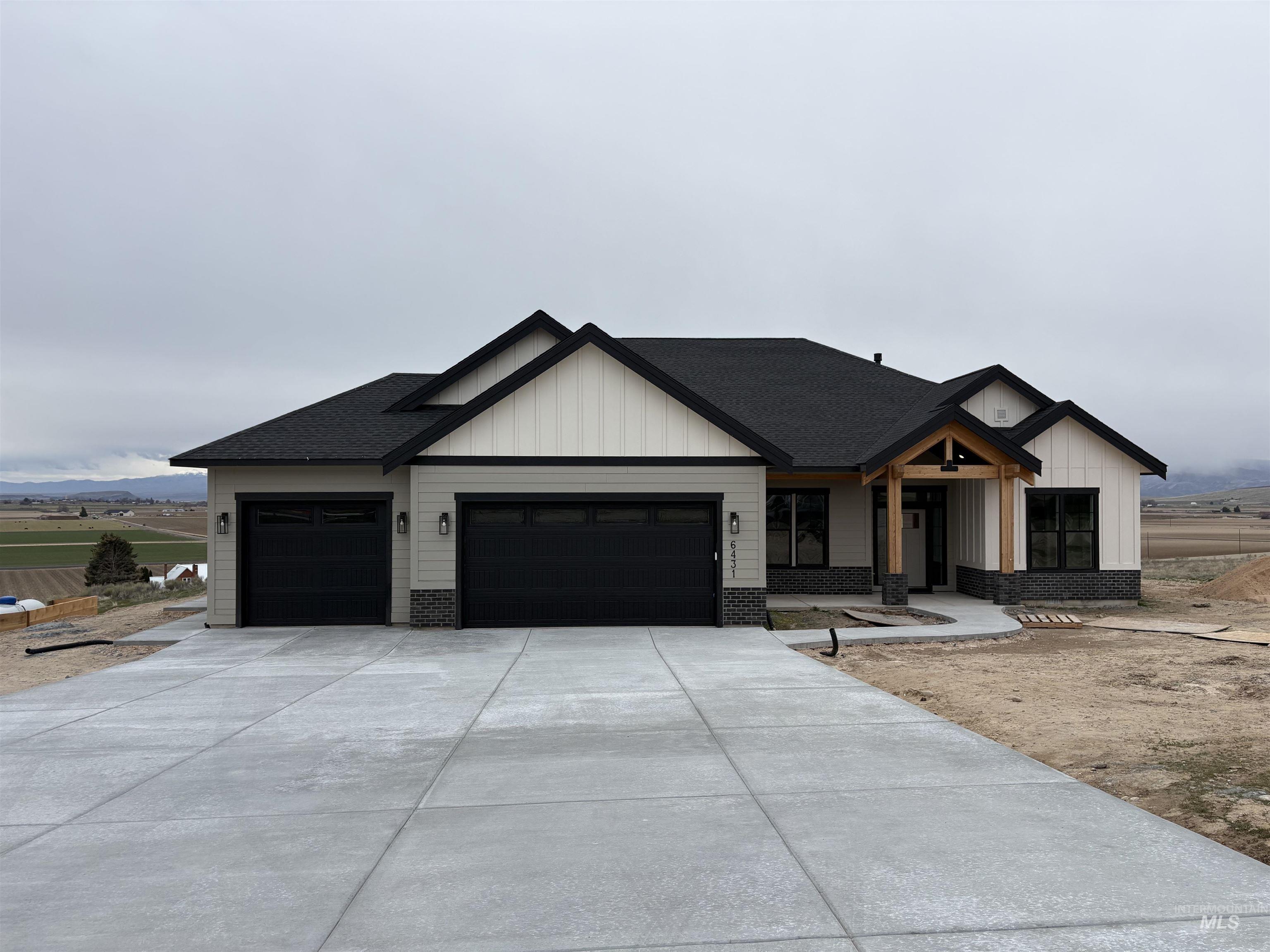Modern inspired farmhouse featuring board and batten siding, an attached garage, concrete driveway, and roof with shingles
