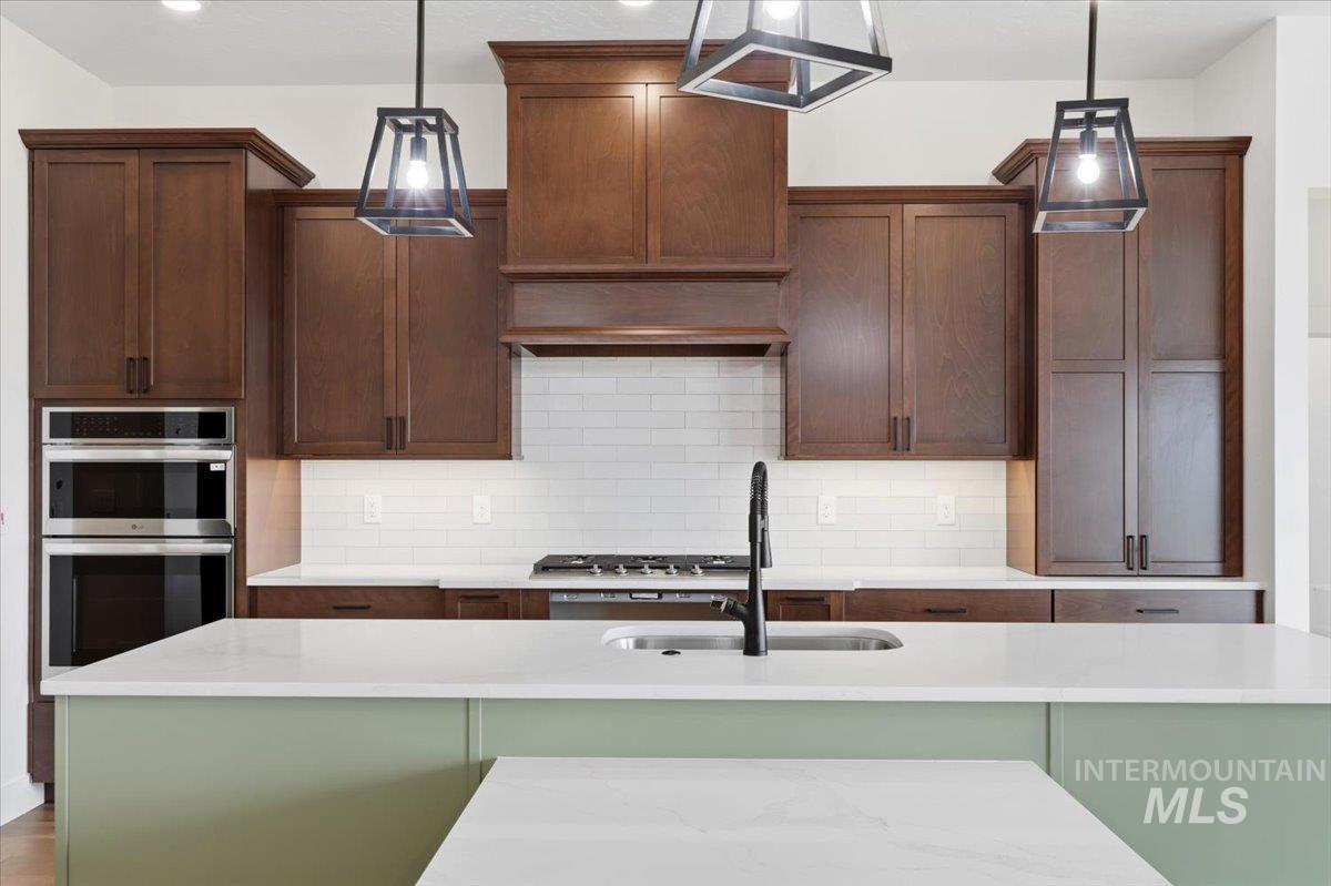 6431 Raptor Ridge Lane Melba, ID 83641 - Photo 19 of 50 Kitchen with a center island with sink, tasteful backsplash, stainless steel double oven, and light stone countertops