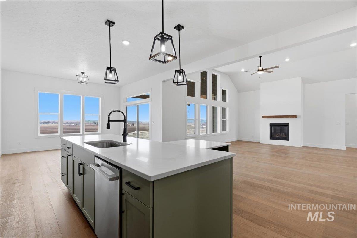 6431 Raptor Ridge Lane Melba, ID 83641 - Photo 48 of 50 Kitchen featuring a glass covered fireplace, light wood finished floors, open floor plan, an island with sink, and vaulted ceiling