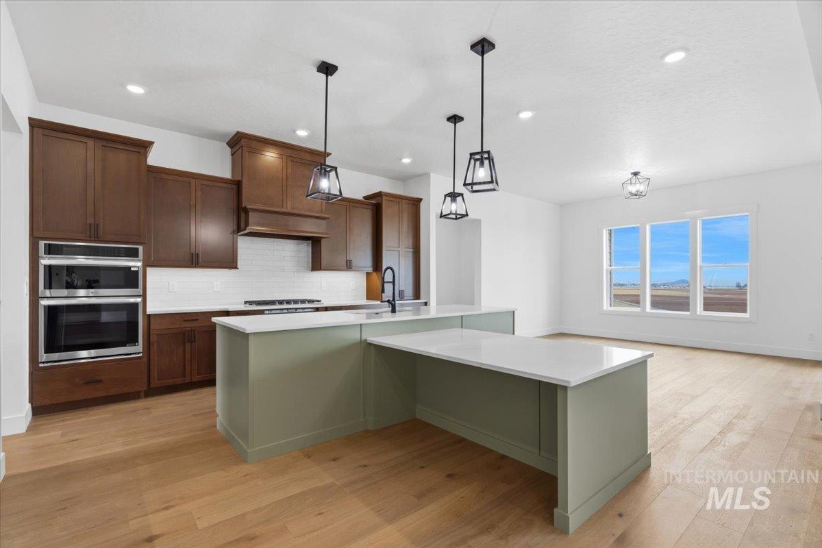 6431 Raptor Ridge Lane Melba, ID 83641 - Photo 22 of 50 Kitchen featuring backsplash, stainless steel appliances, decorative light fixtures, and light wood finished floors