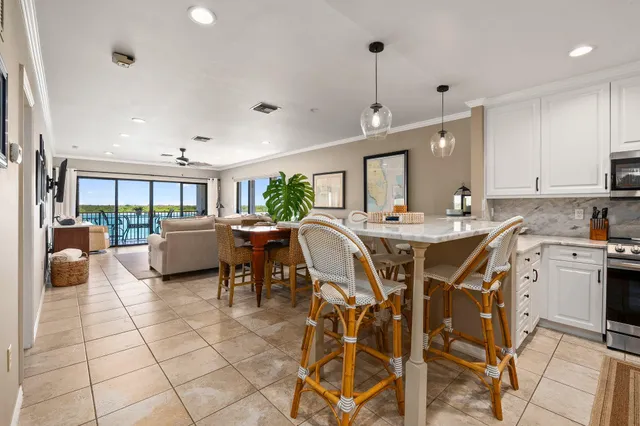 a open kitchen with stainless steel appliances granite countertop a stove a sink a dining table and chairs with white cabinets