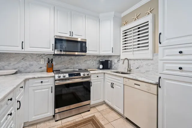 a kitchen with granite countertop white cabinets and white stainless steel appliances