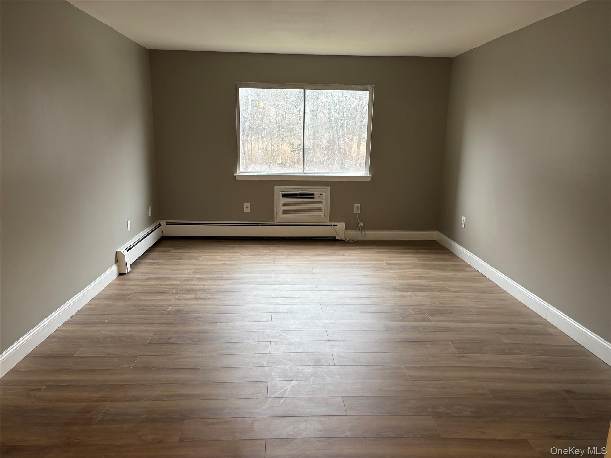 43 Tanager Road, Unit 4303 Monroe, NY 10950 - Photo 2 of 9 Unfurnished room featuring light wood-type flooring, a baseboard radiator, and a wall mounted air conditioner
