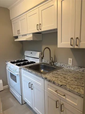 a kitchen with granite countertop a sink and white cabinets