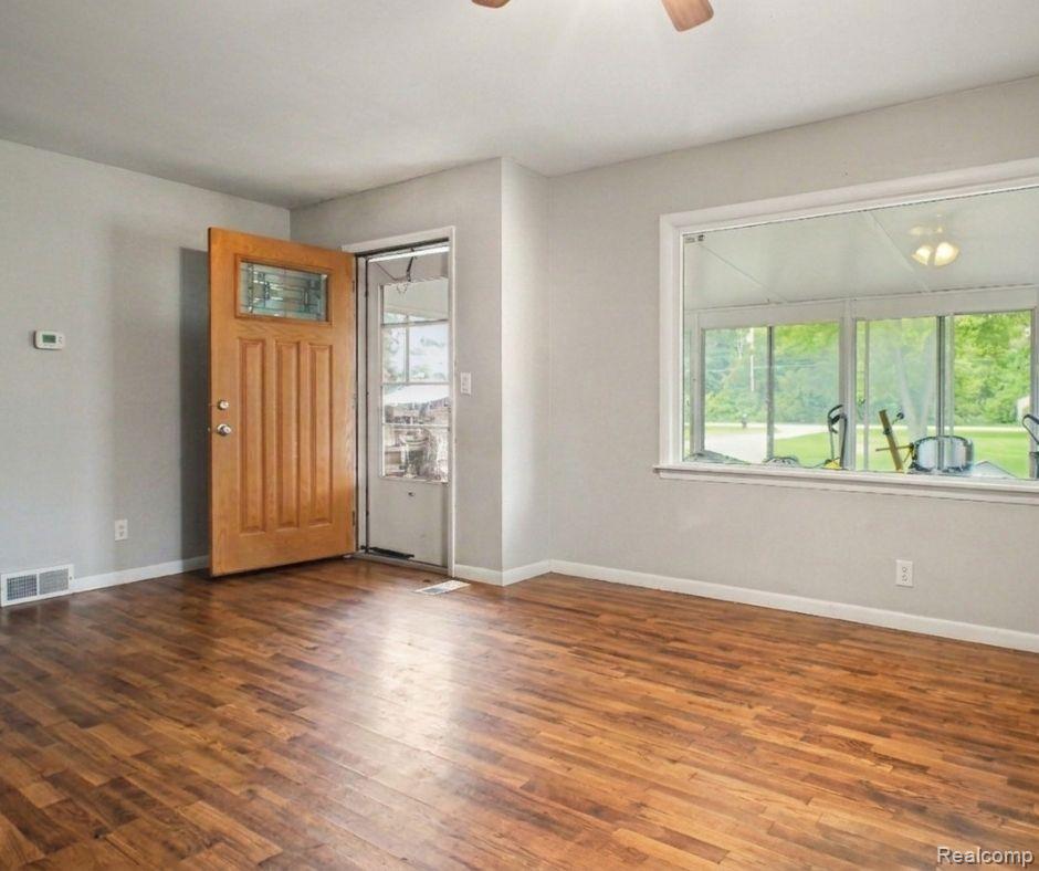 5082 North Center Road Flint, MI 48506 - Photo 2 of 21 Wood-finish flooring, light grey wall paint, wood paneled entry door with decorative glass, and a wide window