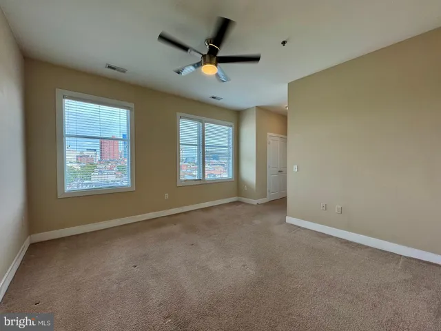 an empty room with windows and ceiling fan