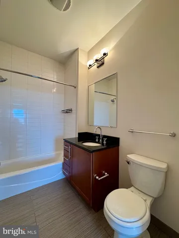 a bathroom with a granite countertop sink a toilet a mirror and bathtub