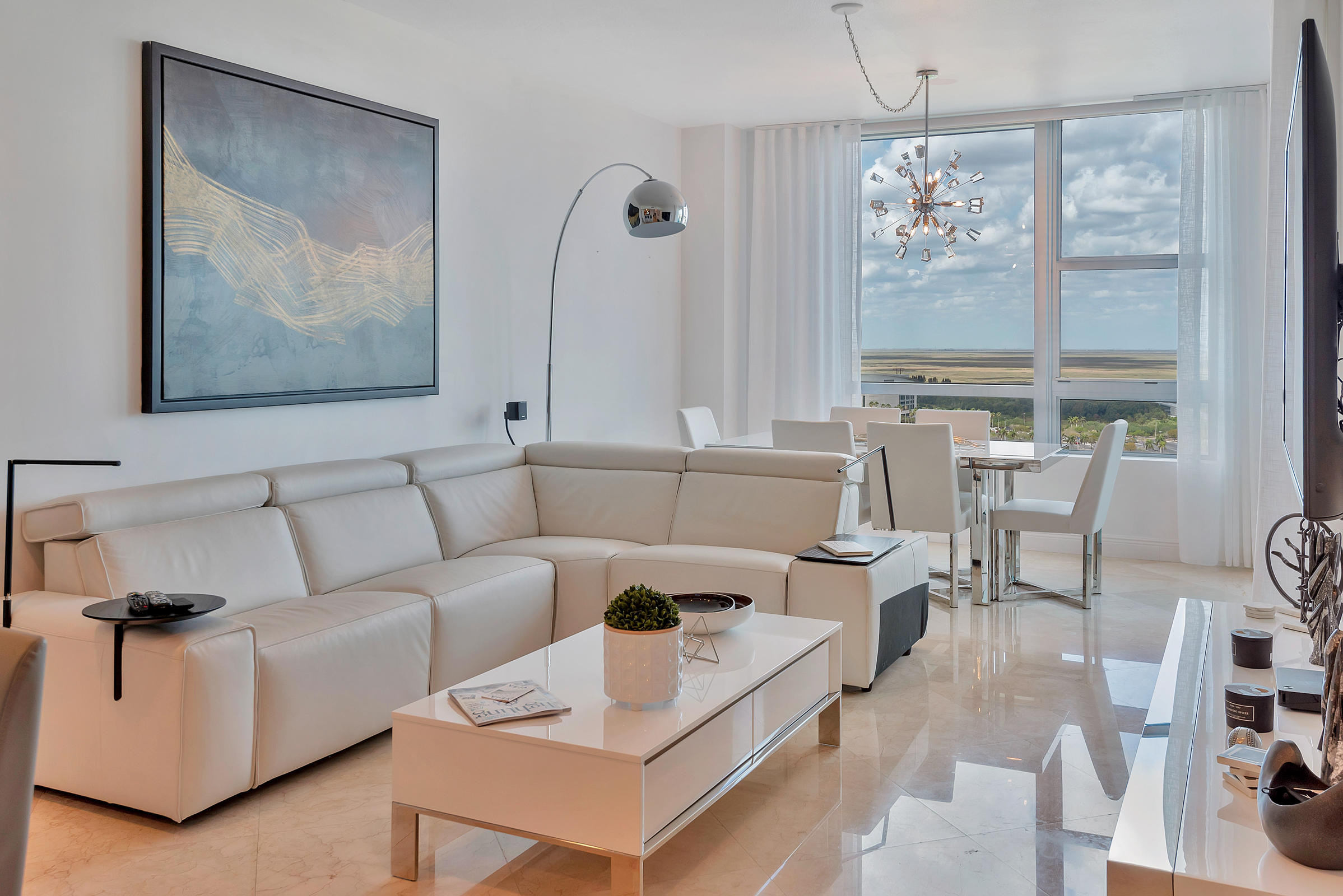a living room with furniture a chandelier and a large mirror