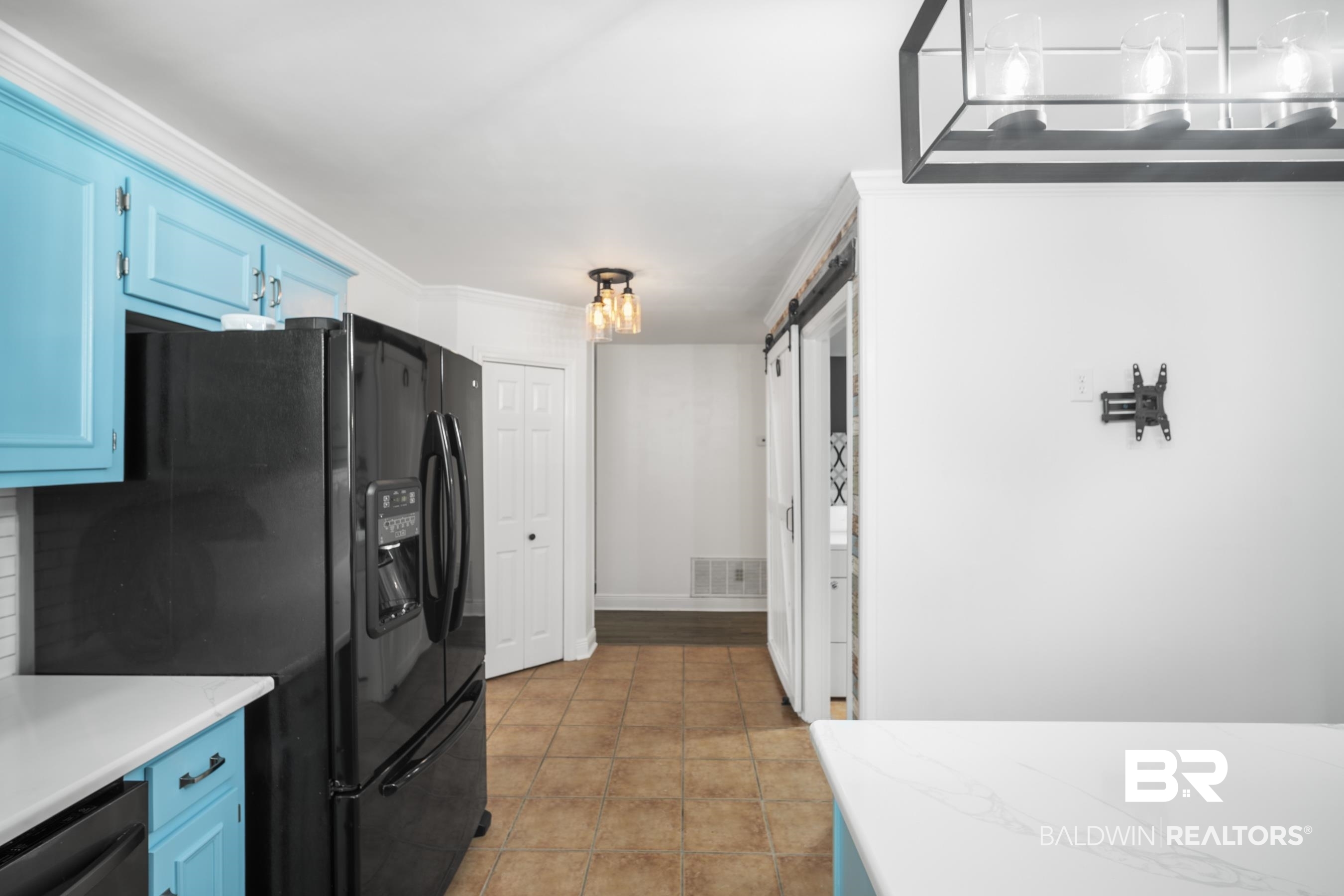 3101 Autumn Ridge Drive West Mobile, AL 36695 - Photo 9 of 36 Kitchen with blue cabinetry, black fridge, a barn door, stainless steel dishwasher, and light tile patterned flooring