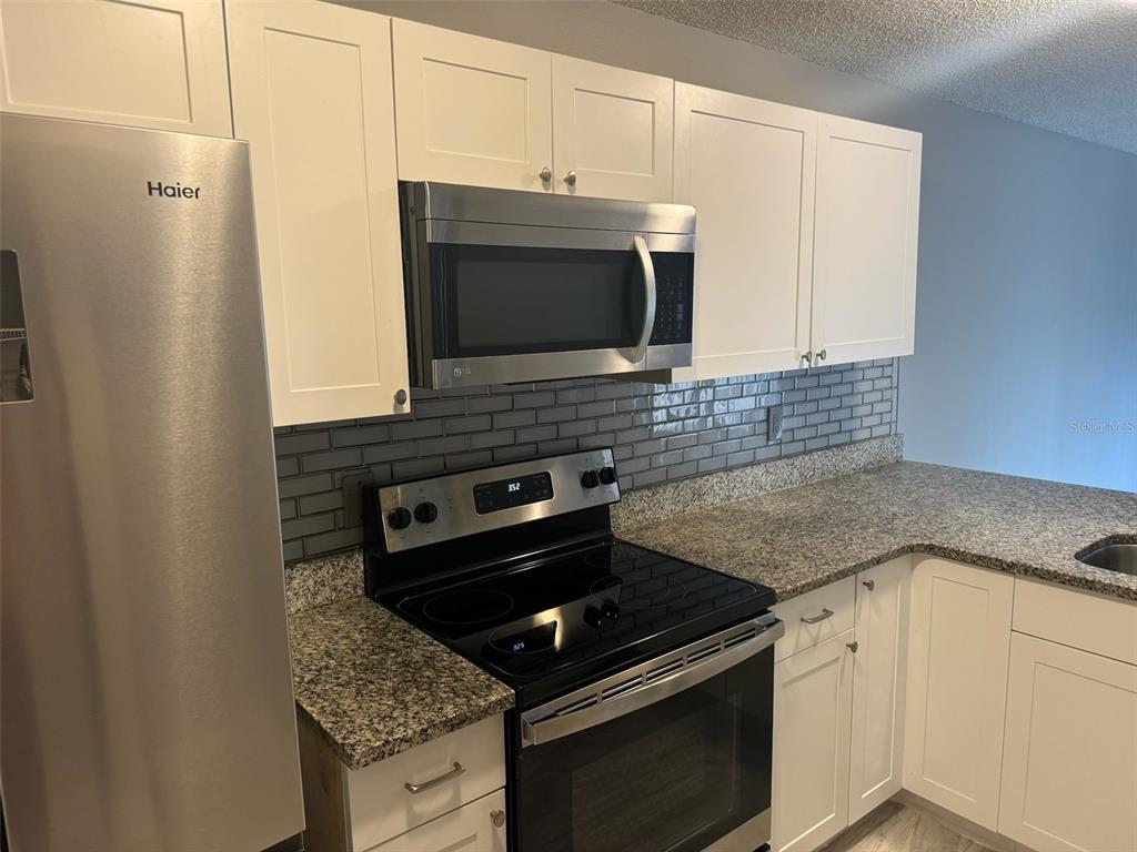 1030 Abada Court Northeast, Unit 110 Palm Bay, FL 32905 - Photo 5 of 14 a kitchen with stainless steel appliances granite countertop a stove microwave and sink