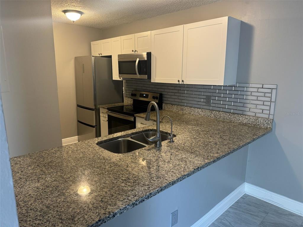 1030 Abada Court Northeast, Unit 110 Palm Bay, FL 32905 - Photo 6 of 14 a kitchen with kitchen island a sink a counter and refrigerator