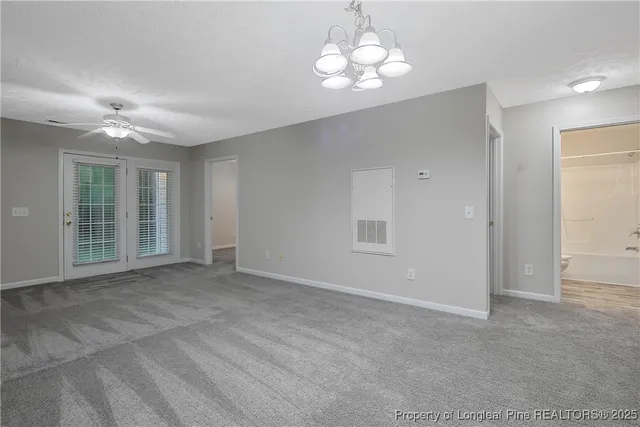 a view of an empty room with a chandelier fan