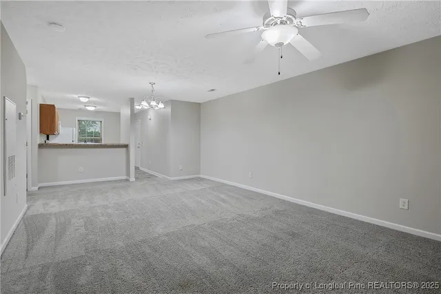 an empty room with a kitchen and a chandelier fan