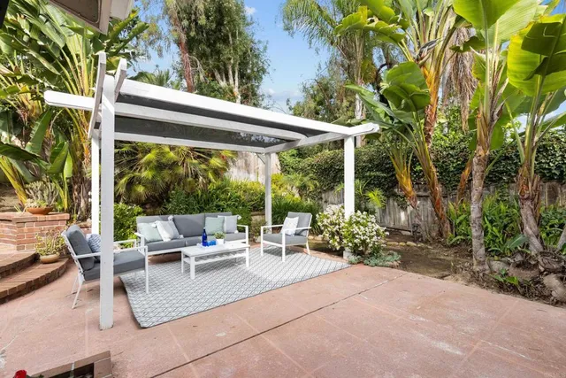 a view of a patio with table and chairs potted plants and floor to ceiling window