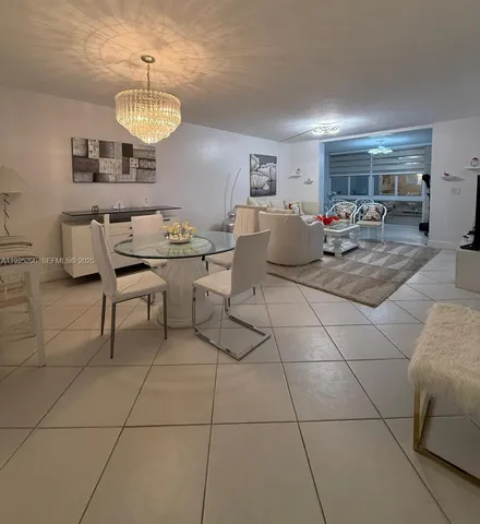 a living room with couches a dining table and a chandelier