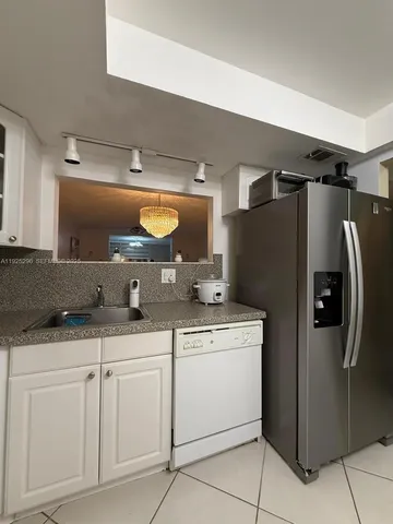 a kitchen with white cabinets and refrigerator
