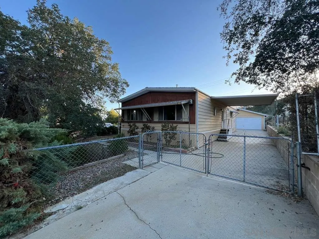 a view of a patio with table and chairs under an umbrella with large trees