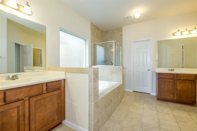 a spacious bathroom with a tub sink and mirror