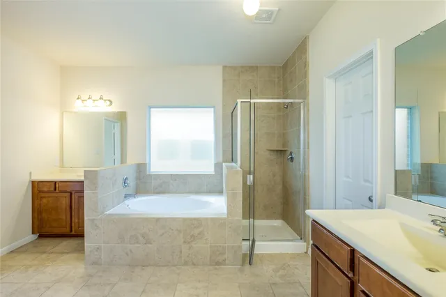 a spacious bathroom with a granite countertop tub sink a shower and a mirror