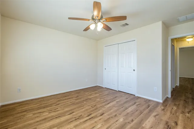 a view of a room with wooden floor and a ceiling fan