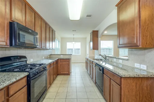 a kitchen with stainless steel appliances granite countertop a stove a sink and a microwave