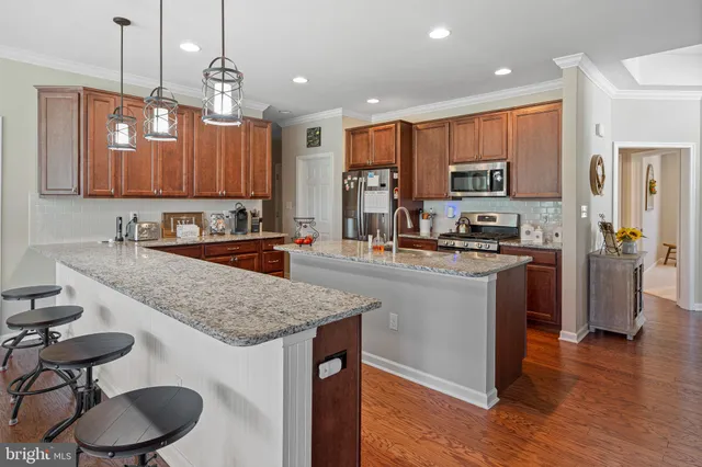 a kitchen with stainless steel appliances granite countertop a sink a stove a refrigerator cabinets and wooden floor