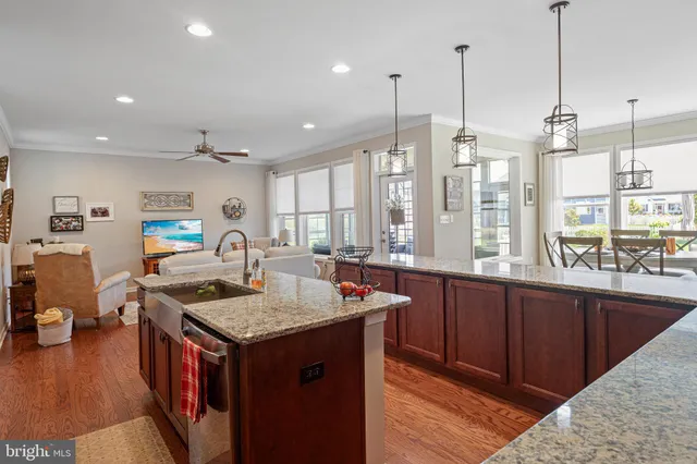 a kitchen with stainless steel appliances granite countertop a sink a stove and a wooden floor